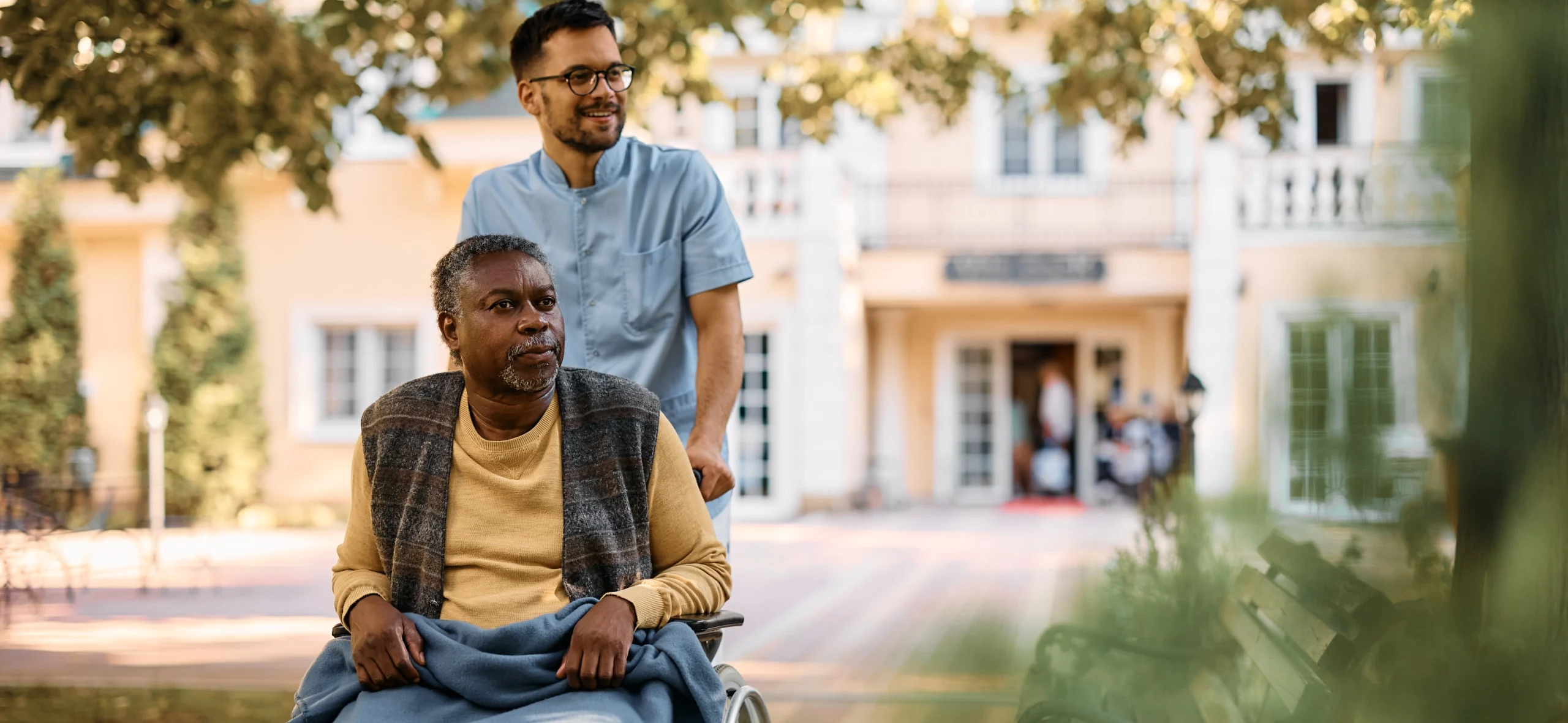 young healthcare worker pushing senior black man